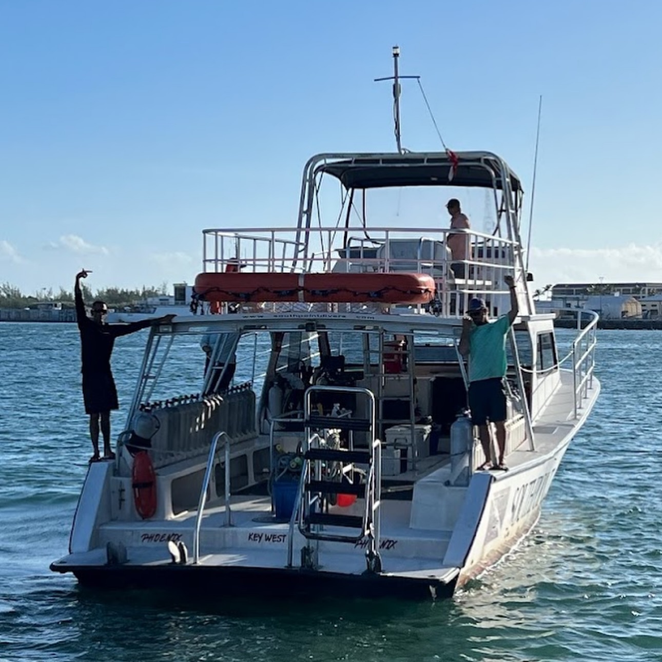 People on a boat in a harbor with clear skies.