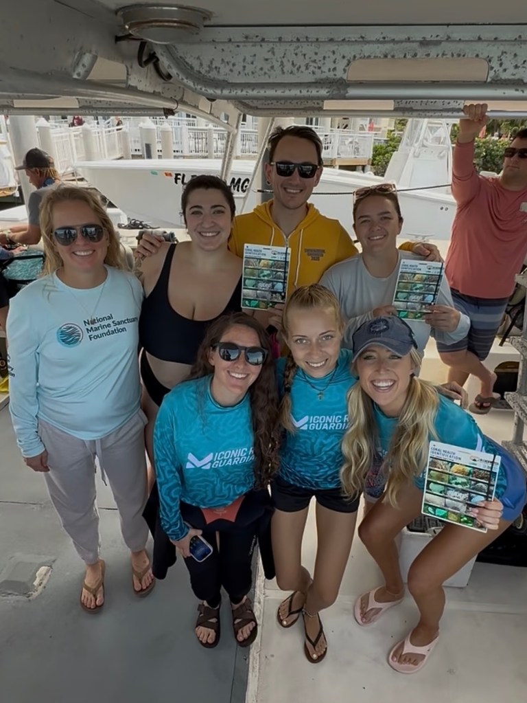 Group of people on a boat smiling, some holding brochures.