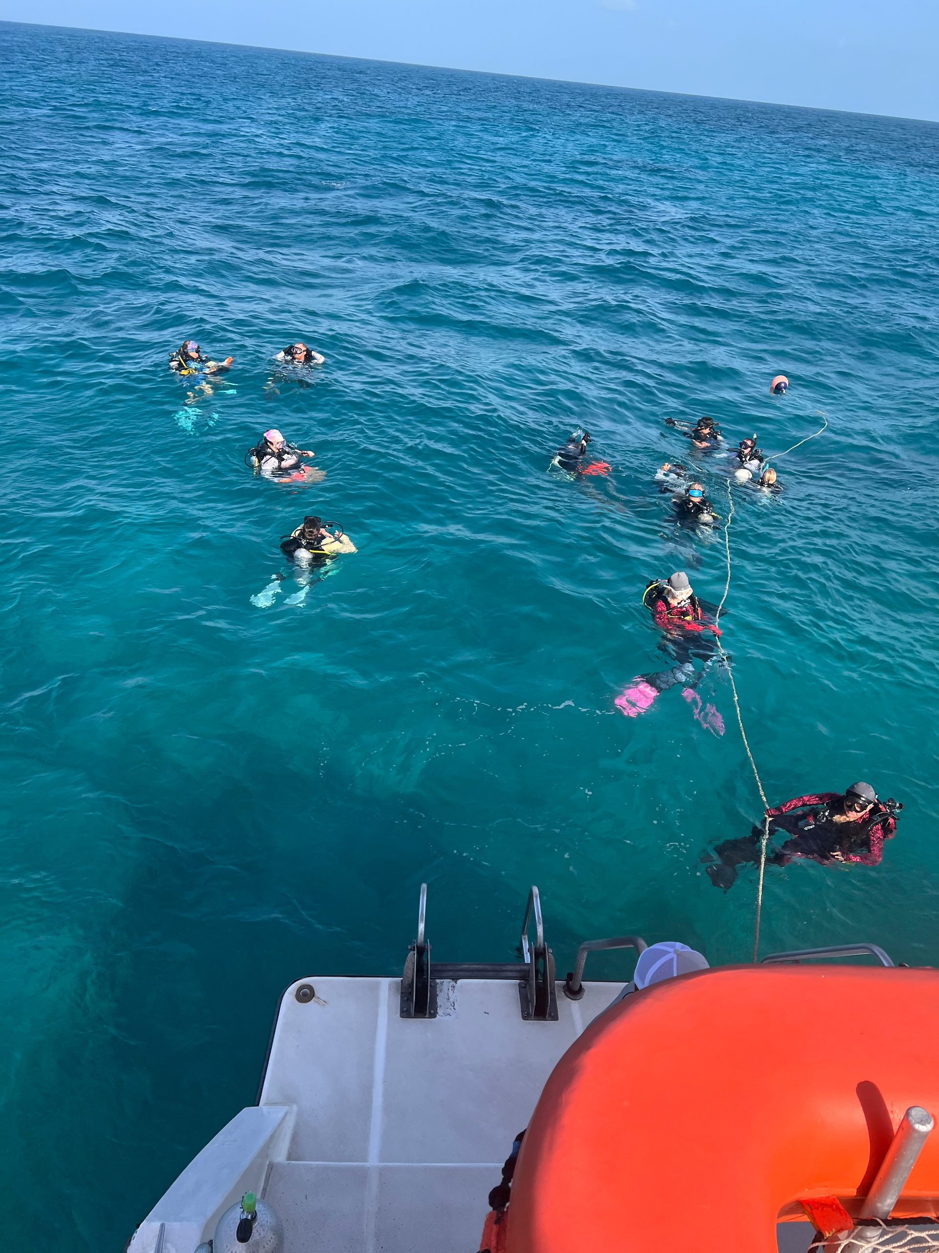 Scuba divers in the ocean near a boat with a life buoy.