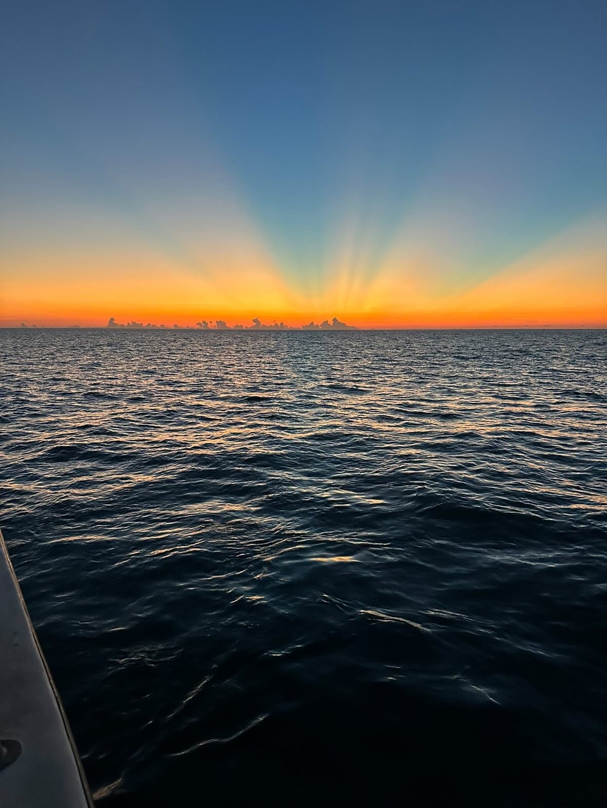 Sunset over ocean with sun rays and clear sky.