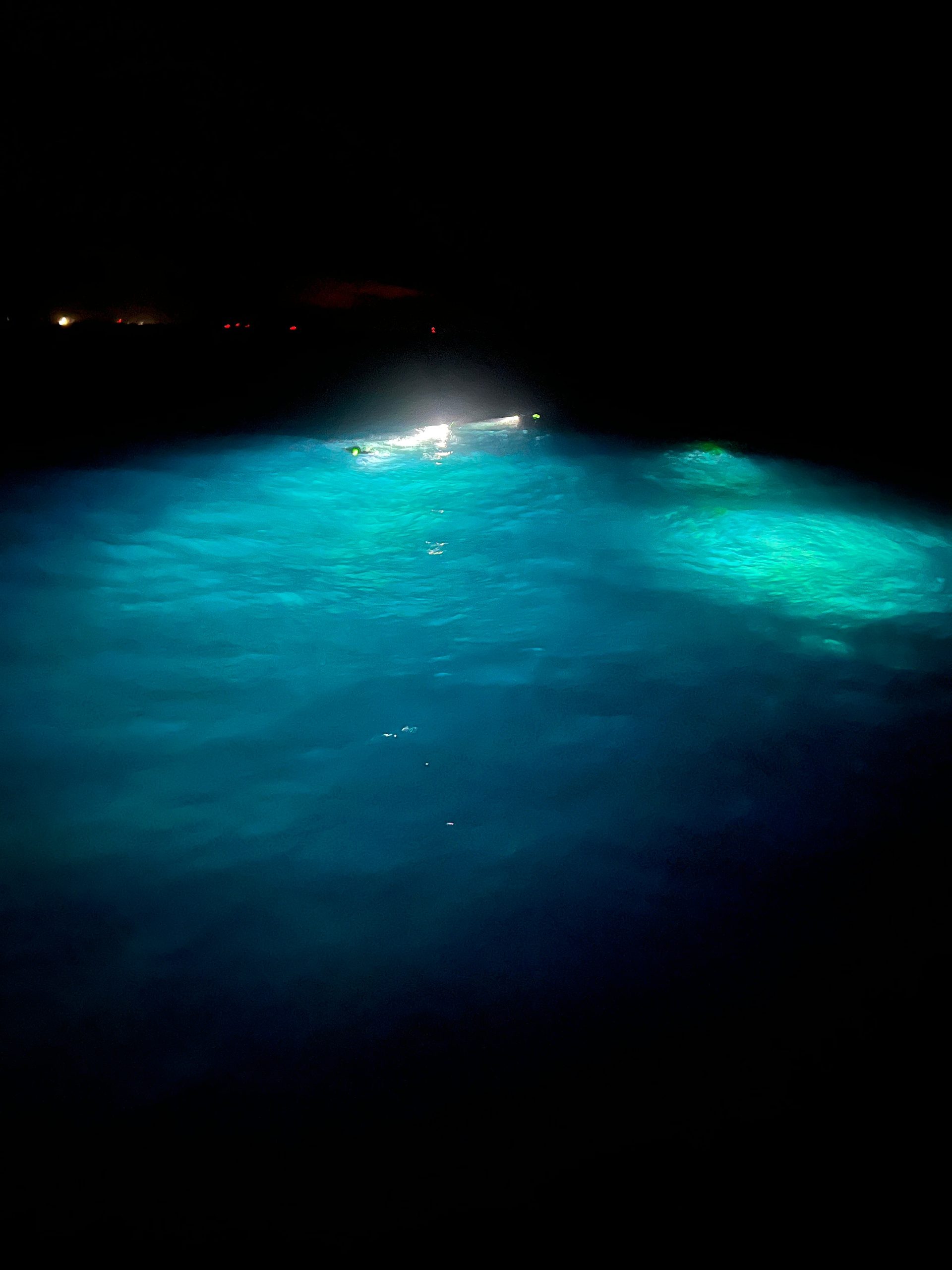 A bright light illuminates the blue water in a dark environment.