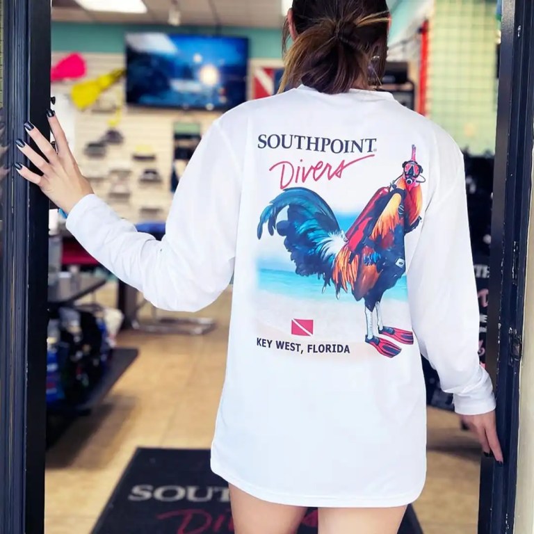 Person in 'Southpoint Divers' shirt with rooster graphic, standing at a store entrance.