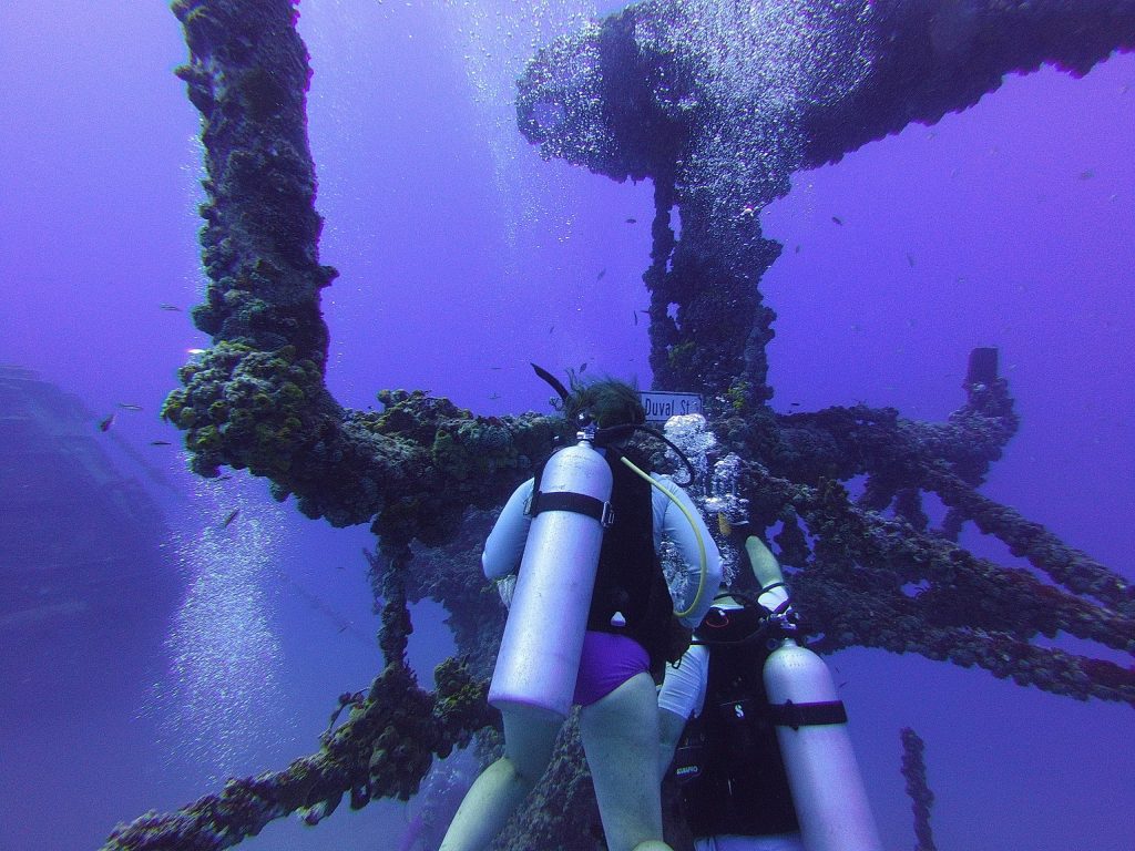 Two scuba divers near an underwater metal structure.