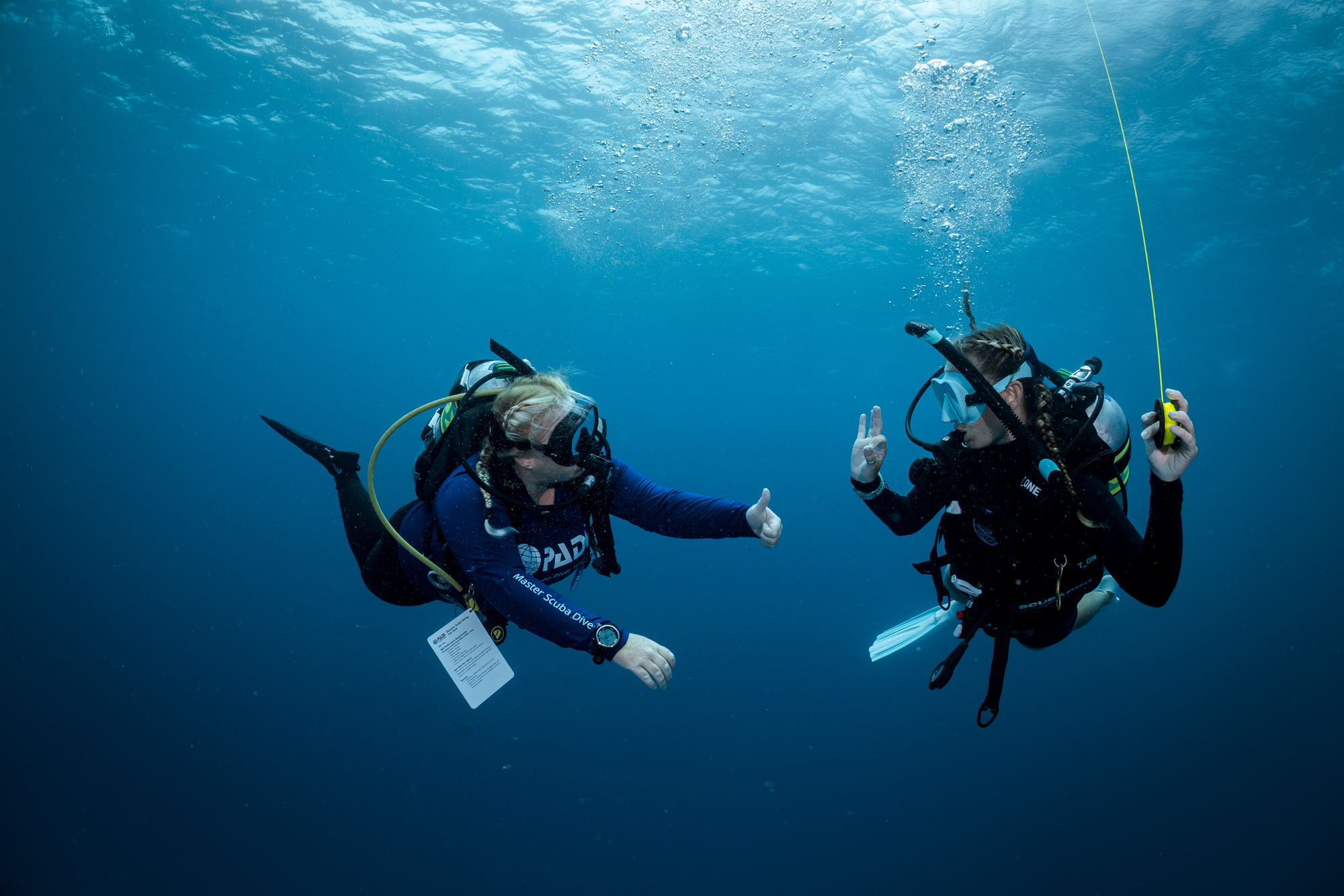 Two scuba divers underwater giving thumbs up gestures.