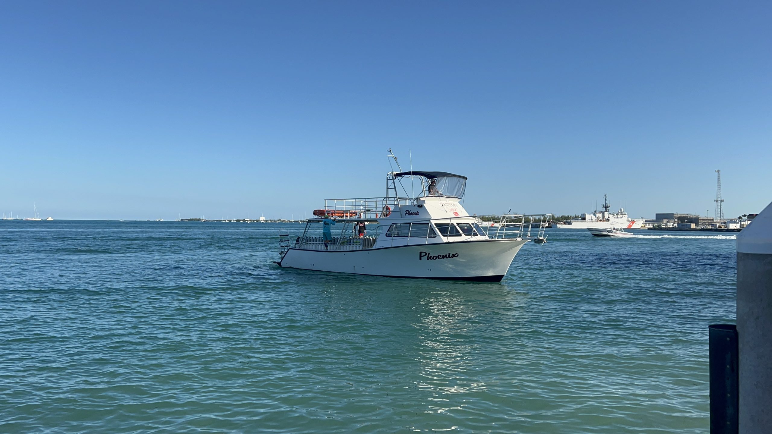 Small boat named Pompona on calm blue water under clear sky.