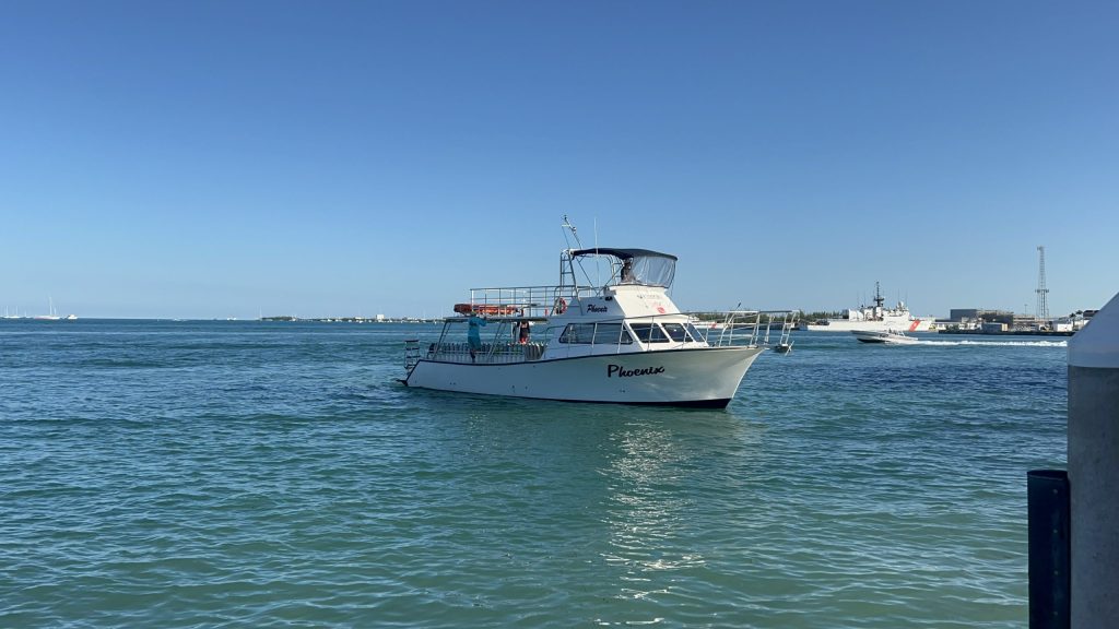 Small boat named Pompona on calm blue water under clear sky.
